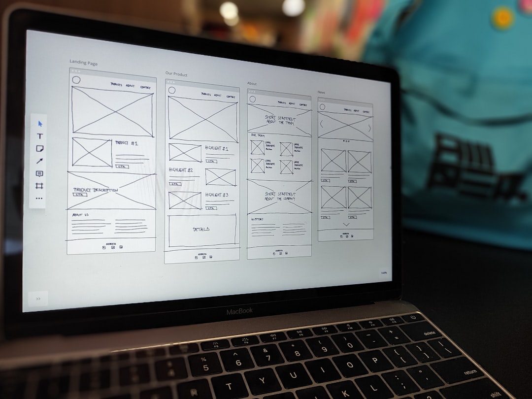 A website wireframe on a macbook screen on an office desk.